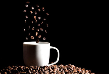 Roasted coffee beans in coffee cup, isolated on black background