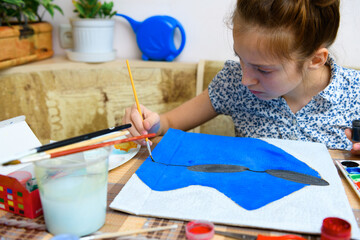 a girl drawing blue gouache cardboard, artistic creation at home, makes creative artwork