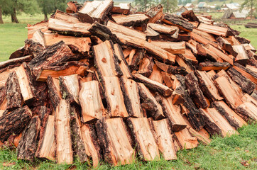 Firewood is stacked in autumn. Chopped pile of wood. Lots of wood from logs. Preparation of firewood for the winter. background texture pattern with stacked dry chopped firewood. Trees in the sawmill