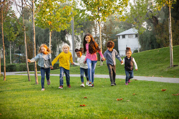 Running. Interracial group of kids, girls and boys playing together at the park in summer day. Friendship has no race. Happiness, childhood, education, diversity concept. Look happy and sincere.