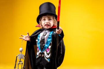 halloween, holiday and childhood concept - boy in dracula costume with black cape and top hat on...