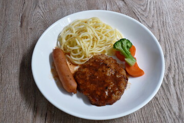 grilled pork burgrer steak and sausage with spaghetti on plate