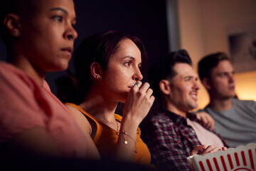 Group Of Friends Eating Popcorn Sitting On Sofa At Home Watching Evening TV And Relaxing Together