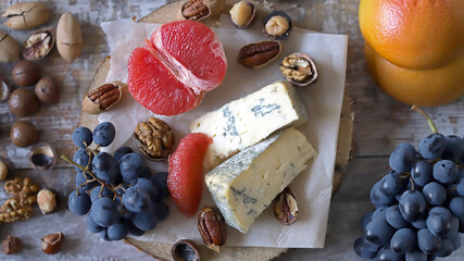 Selective focus. Cheese, nuts and fruits. Cheese snack on a wooden stand. Wine appetizer.