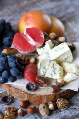 Selective focus. Cheese, nuts and fruits. Cheese snack on a wooden stand. Wine appetizer.
