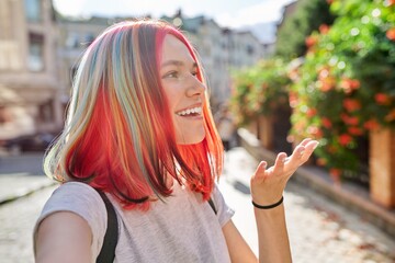 Fashionable teenage girl looks at webcam and talks on city street