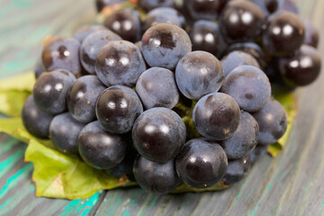 Bunches of dark blue grapes. Lies on black-green pine boards.