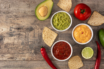 Traditional Mexican sauces. Guacamole, chilli pepper sauce and cheese sauce on wooden table