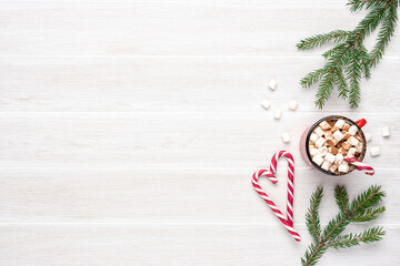 Obraz premium Hot cocoa with marshmallows and candy canes on white wooden slatted background. Copy space, top view