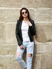 Young girl in trendy retro 90s style leather jacket and jeans on street of old city