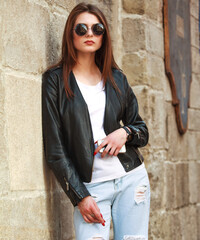 Young girl in trendy retro 90s style leather jacket and jeans on street of old city