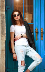 Young girl in trendy retro 90s style leather jacket and jeans on street of old city