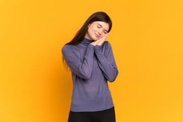Young Ukrainian girl isolated on yellow background making sleep gesture in dorable expression