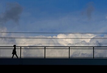 clouds over a bridge with silhouetted person - 387183112