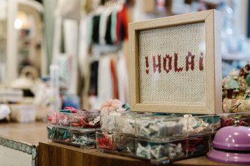 Wool crochet with the word Hello in Spanish ( Hola ) with a fuzzy background of a haberdashery and accessories. Rign bell pink. © JavierBallesterLegua