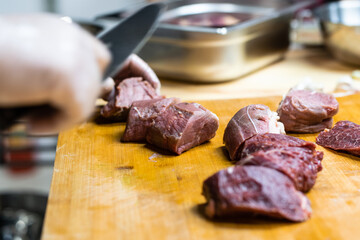 the cook cuts raw meat into medallions
