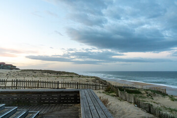 Obraz premium sand dunes and waves breaking on an endless beach under a stormy sky