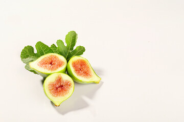 Three fig halves on fig leaves isolated on white background horizontal arrangement