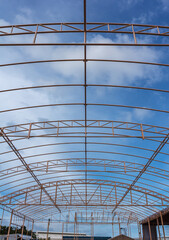 Details of steel roof frame with blue sky and clouds.