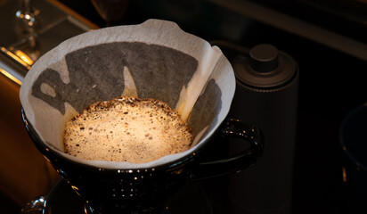 The barista is preparing coffee beans and dripping equipment.