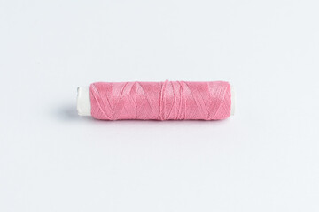 One vivid pink cotton spool of thread isolated on a white table.