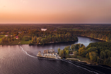Aerial view of Koknese castle ruins at colorful sunset. Medieval ruins on the shore of river surrounded by forest.  