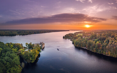 Fototapeta premium Aerial view of Koknese castle ruins at colorful sunset. Medieval ruins on the shore of river surrounded by forest. 