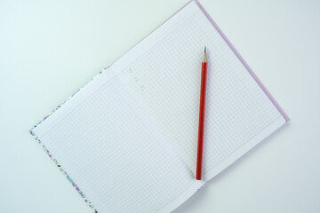 Notebook and red pencil lying on white table, goal setting and planning concept
