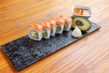 sushi roll filled with avocado, cream cheese and salmon topping