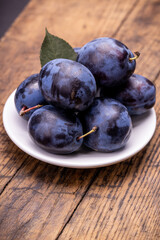 heap of a purple damsons plums over grunge wooden background. natural fruits. healthy eating concept
