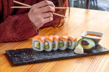 sushi roll filled with avocado, cream cheese and salmon topping