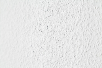 Closeup of uniform white roughly textured wall and selective focus