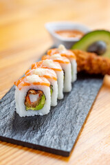 sushi roll filled with avocado, cream cheese and salmon topping