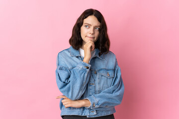 Teenager Ukrainian girl isolated on pink background having doubts and thinking