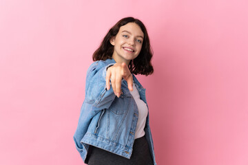 Teenager Ukrainian girl isolated on pink background pointing front with happy expression