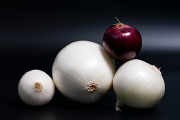 In the center of the screen is a group of fresh red-purple and white onion heads. Arranged in the form of a slide.