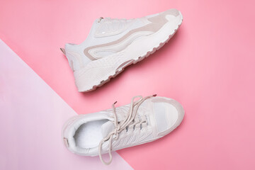 Beige women's sneakers on pink background.