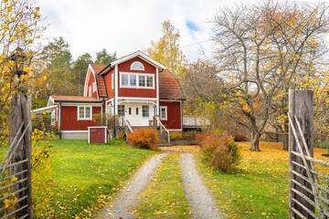 Old traditional red wooden house in Sweden. Countryside in autumn day.View of beautiful European garden design. Golden, yellow, brown, red colors of leaves