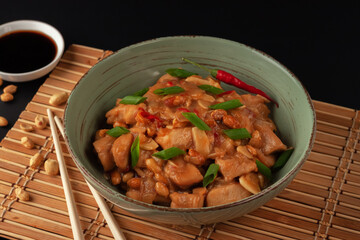 Kung Bao chicken on a black background. A Chinese dish with chicken, chili, peanuts, sauces and onions.