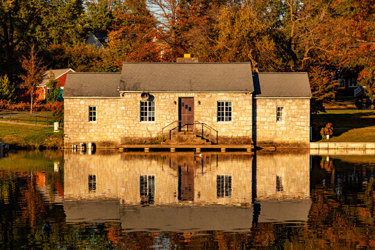 The historic stone lake house by the Culler Lake in Baker Park in autumn. Background has meadow, trees, autumn colors while the lake has full scenic reflection of house.