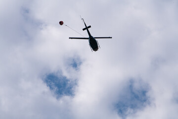 A helicopter transports water to drop on a wildfire