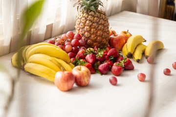 delicious fresh fruits on a white background and table, pineapple, bananas, apple, strawberry, grapes and bananas, healthy lifestyle, studio 
