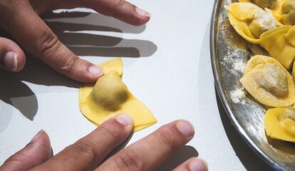 Closeup of hand making fresh pasta tortellini