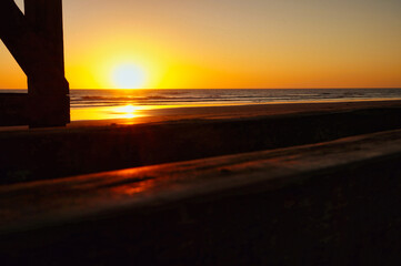 Naklejka na ściany i meble Sunrise from beneath an old wooden pier in La Lucila beach, Buenos Aires.