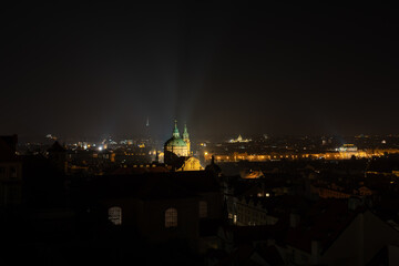 
the dome of the old church of St. Nicholas in the center of Prague at night and the surrounding architecture and light from the street lights