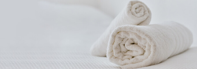 Folded white towels on bed, close up view