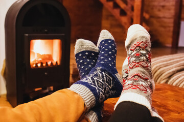 Feet in wool socks warming near fireplace in rustic cabin house. Cozy winter.