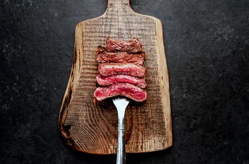Foto auf Alu-Dibond Different degrees of roasting steak on a meat fork on a stone background © александр таланцев