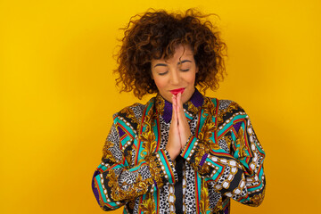 Indoor closeup of beautiful European woman isolated on gray background practicing yoga and meditation, holding palms together in namaste mudra, looking calm, relaxed and peaceful.