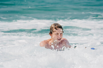 Fototapeta na wymiar Teenage boy having fun with surfboard in waves of Atlantic Ocean